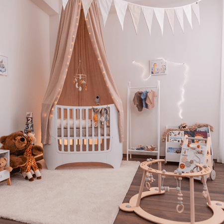 Babyzimmer mit weißem Babybett und rosa Betthimmel