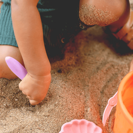 Kleines Kind buddelt im Sand