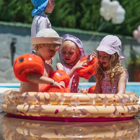 Drei Kinder die in einem Planschbecken fröhlich spielen